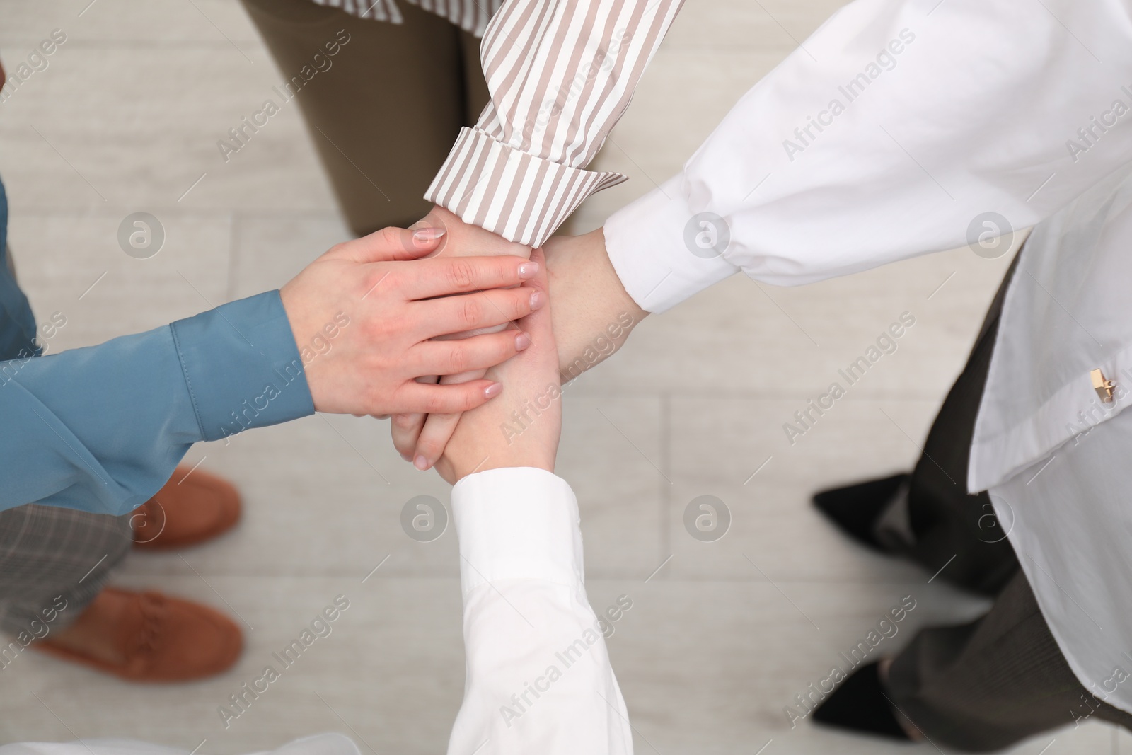 Photo of Business concept. Group of people stacking hands indoors, above view