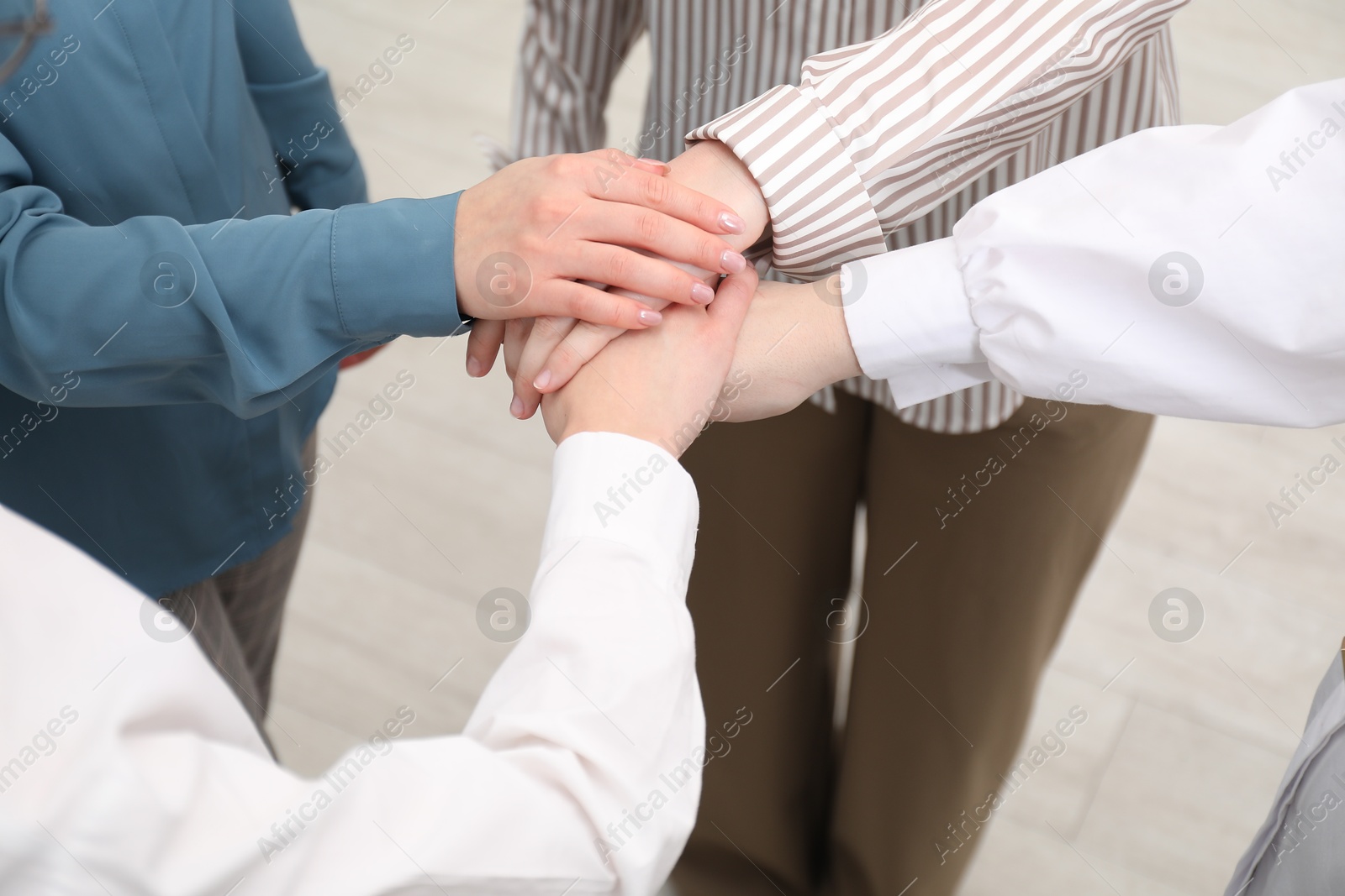 Photo of Business concept. Group of people stacking hands indoors, closeup