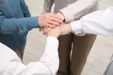 Photo of Business concept. Group of people stacking hands indoors, closeup