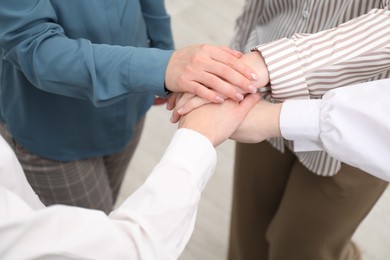 Photo of Business concept. Group of people stacking hands indoors, closeup