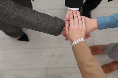 Photo of Business concept. Group of people stacking hands indoors, above view. Space for text