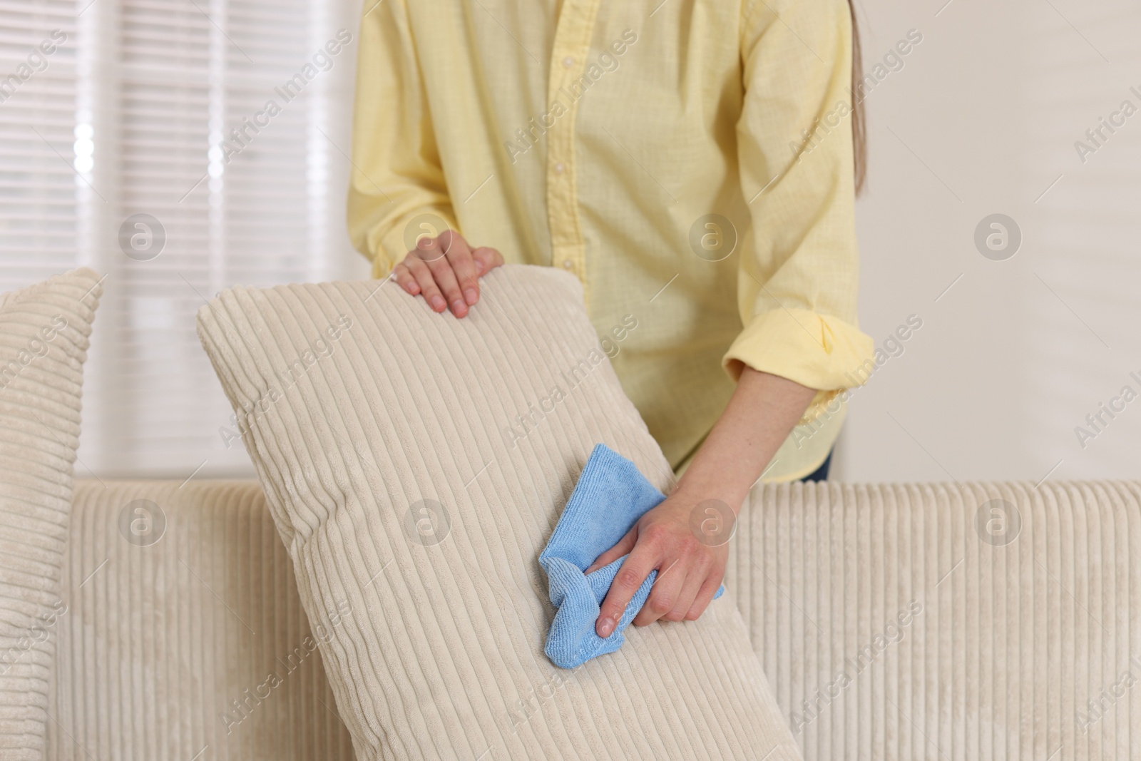 Photo of Woman cleaning sofa cushion with rag at home, closeup