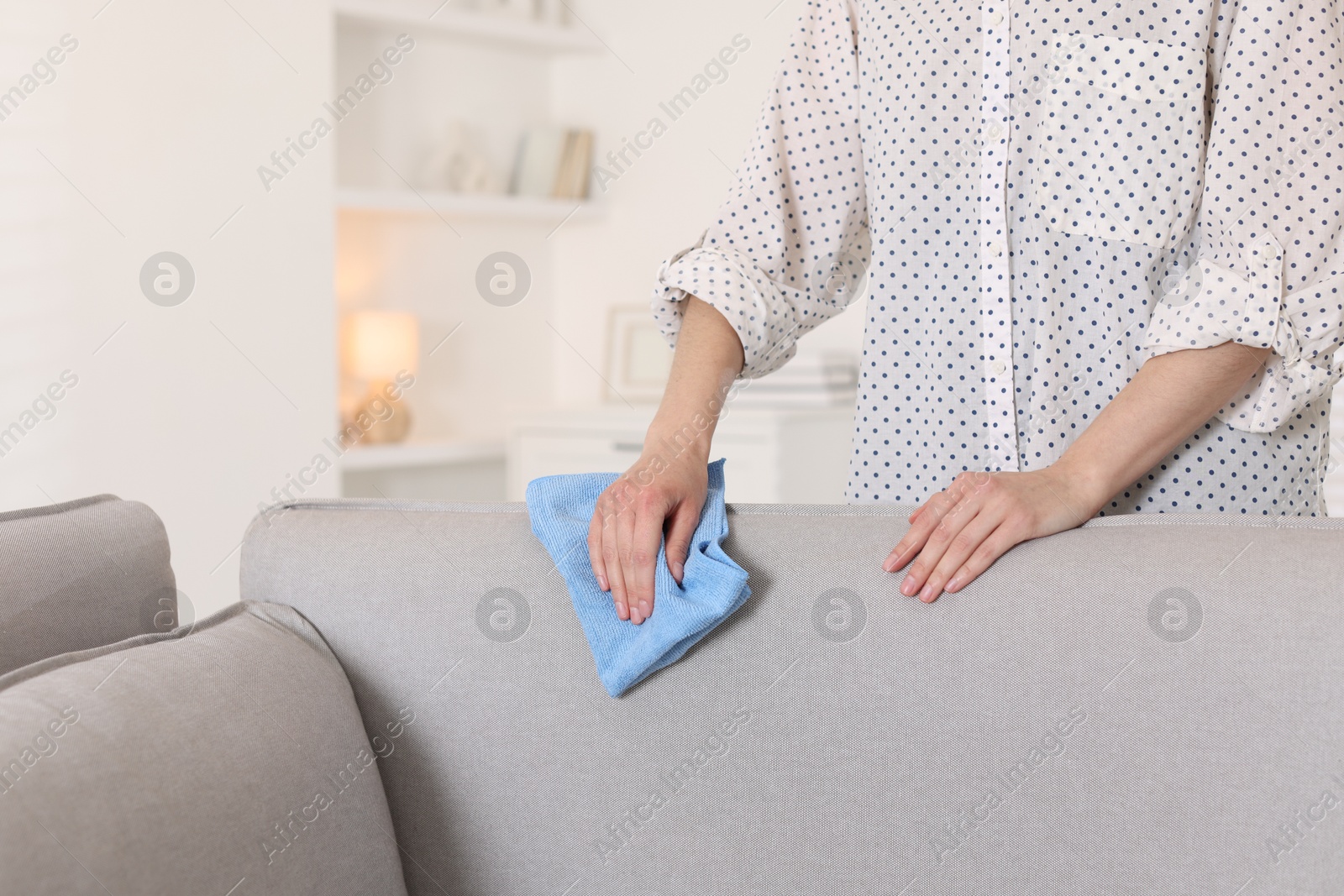 Photo of Woman cleaning sofa with rag at home, closeup