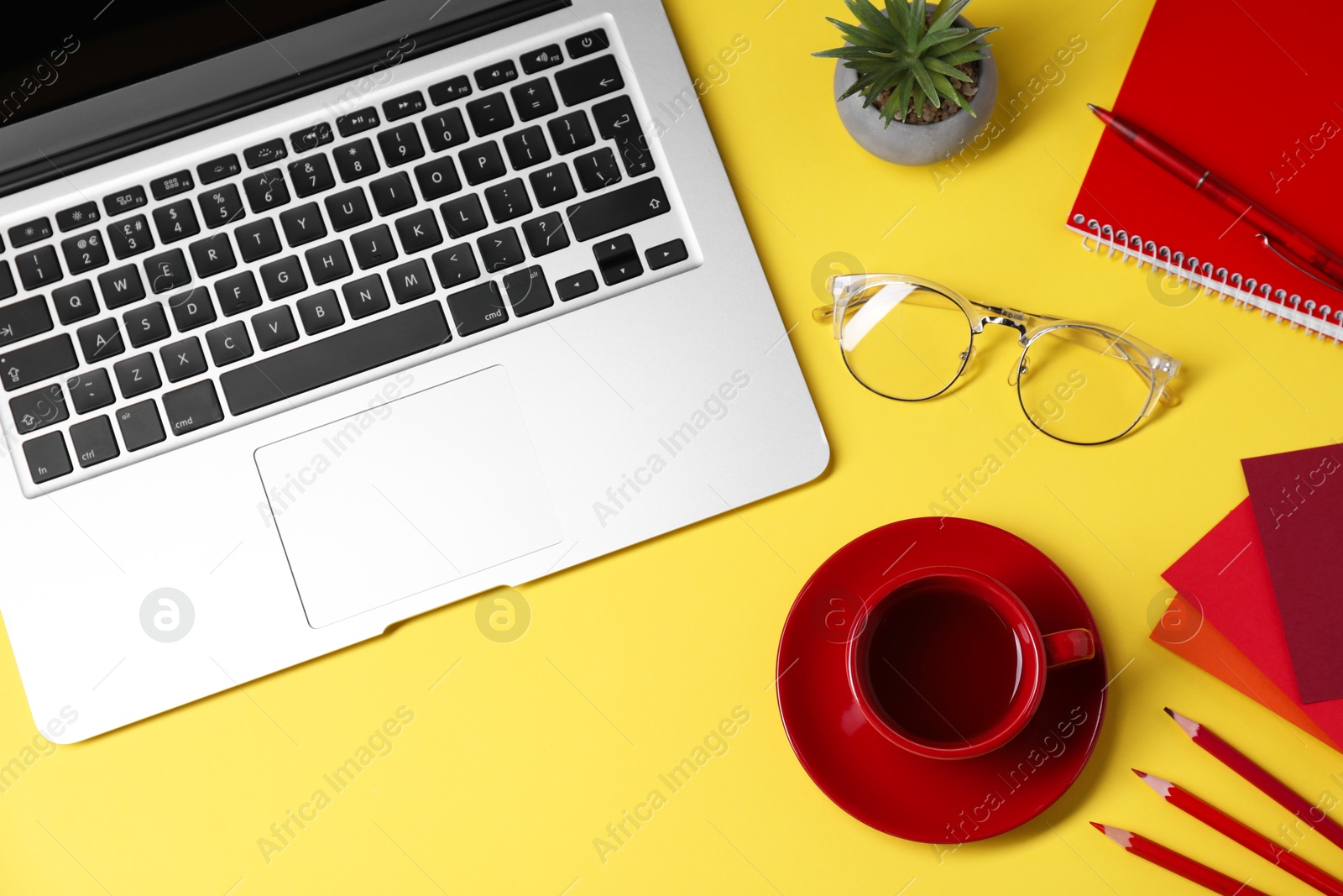 Photo of Designer's workplace. Flat lay composition with stationery, laptop and cup of coffee on yellow background