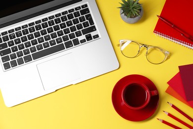 Photo of Designer's workplace. Flat lay composition with stationery, laptop and cup of coffee on yellow background