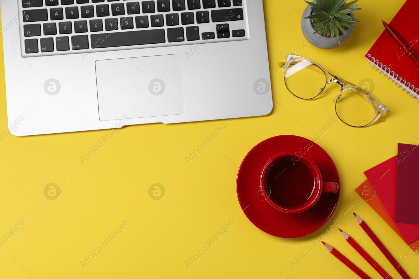 Photo of Designer's workplace. Flat lay composition with stationery, laptop and cup of coffee on yellow background, space for text