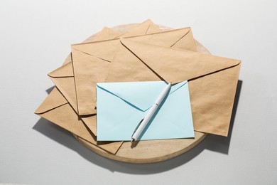 Photo of Paper envelopes and pen on grey background, above view. Mockup for design