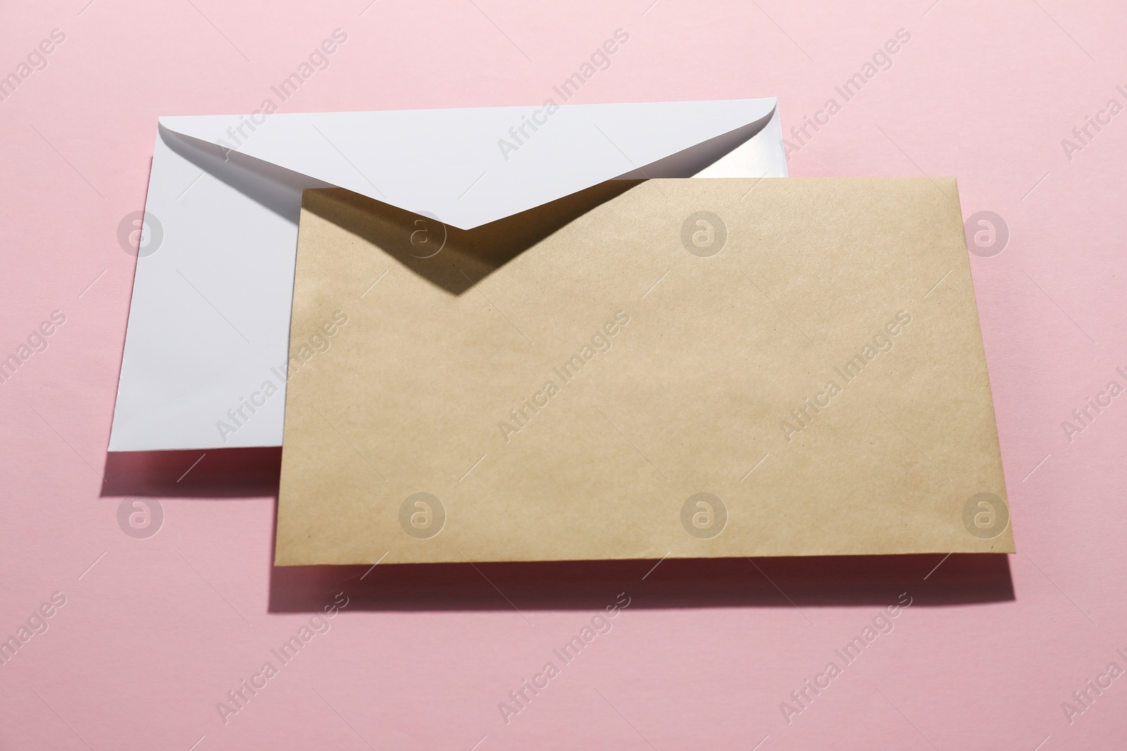 Photo of Paper envelopes on pink background, above view. Mockup for design