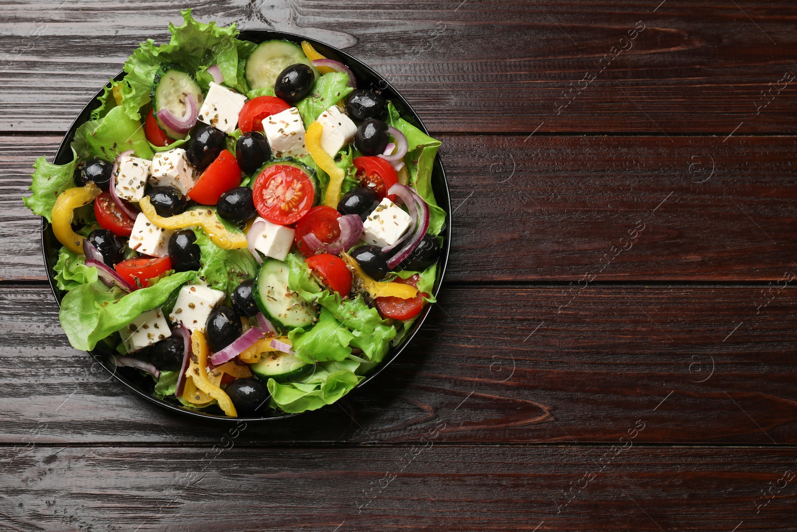 Photo of Delicious fresh Greek salad on wooden table, top view. Space for text