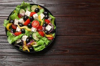 Photo of Delicious fresh Greek salad on wooden table, top view. Space for text