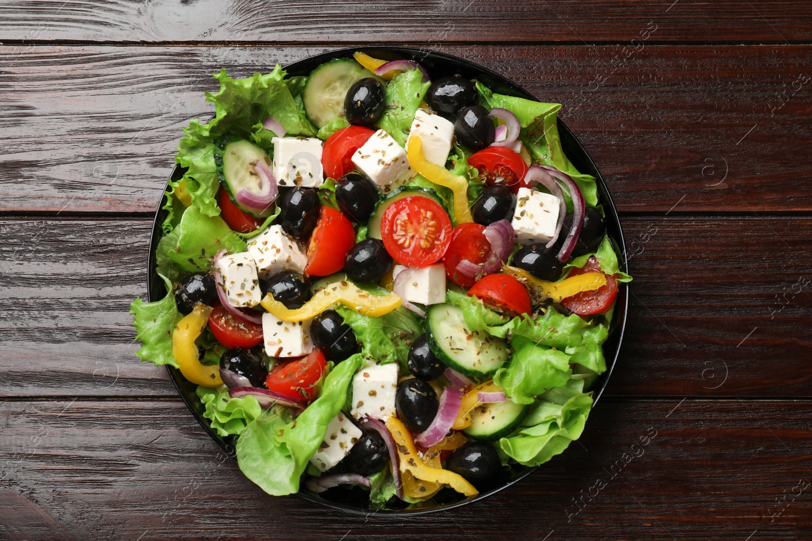 Photo of Delicious fresh Greek salad on wooden table, top view