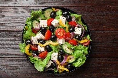 Photo of Delicious fresh Greek salad on wooden table, top view