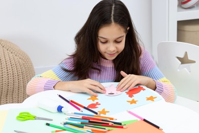 Photo of Girl making art project at table indoors