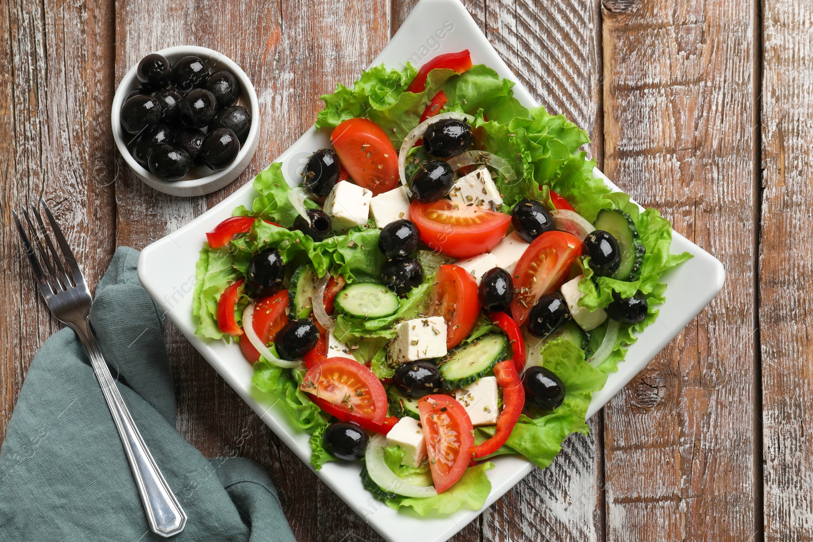 Photo of Delicious fresh Greek salad on wooden table, top view