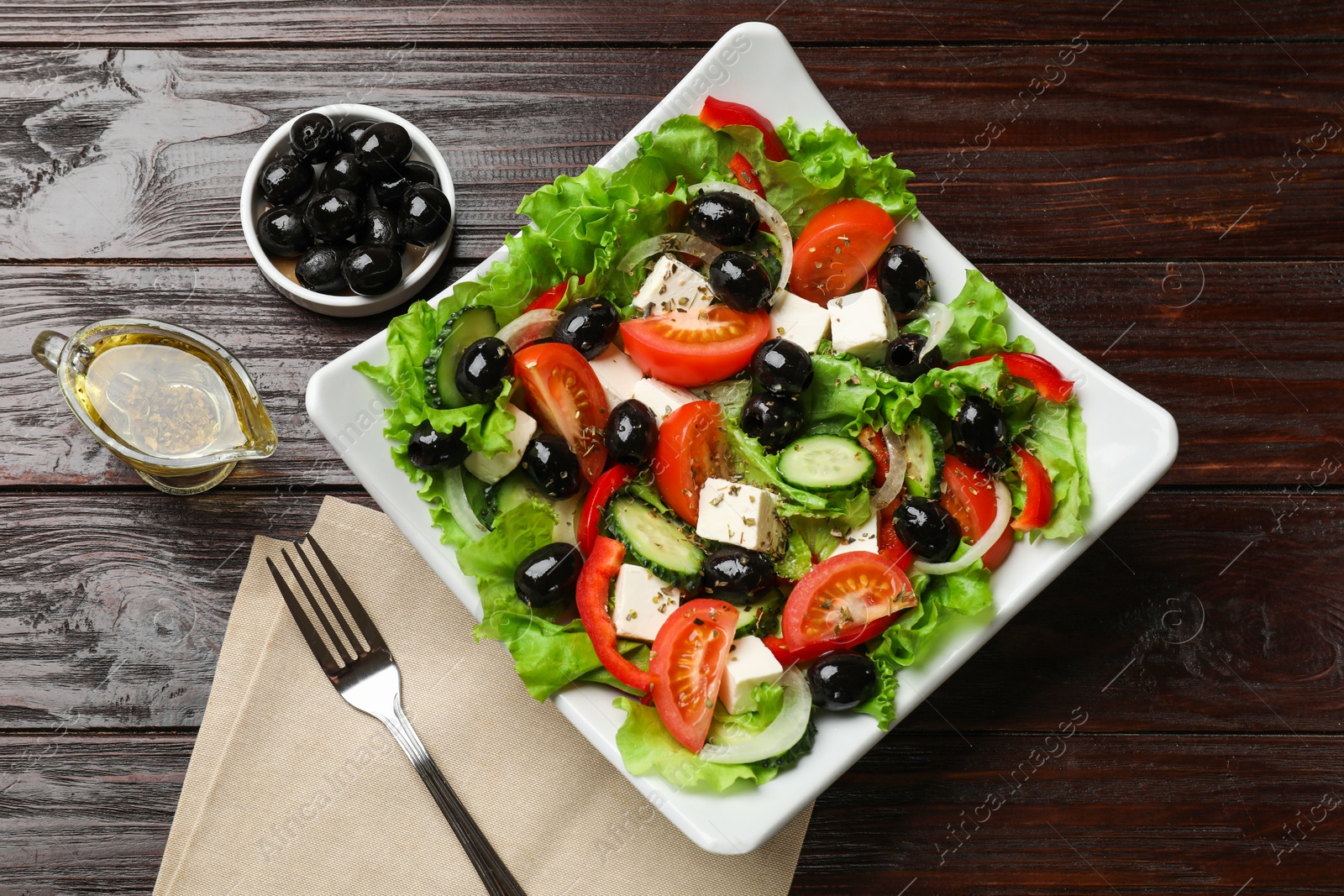 Photo of Delicious fresh Greek salad on wooden table, top view