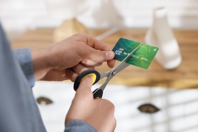 Photo of Man cutting his credit card indoors, closeup