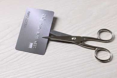 Photo of Credit card and scissors on white wooden table, above view