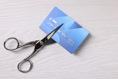 Photo of Credit card and scissors on white wooden table, top view