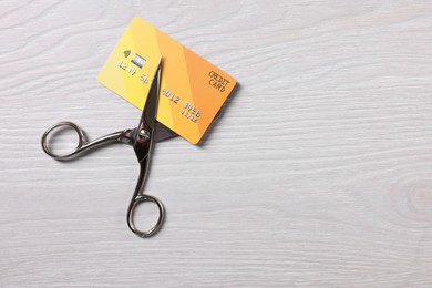 Photo of Credit card and scissors on white wooden table, top view. Space for text