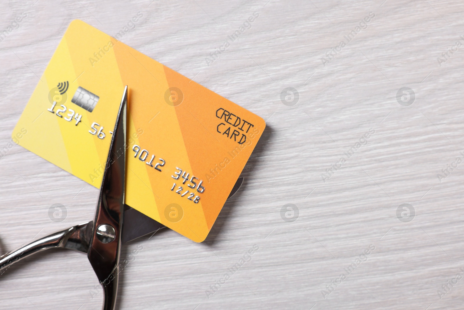 Photo of Credit card and scissors on white wooden table, top view. Space for text