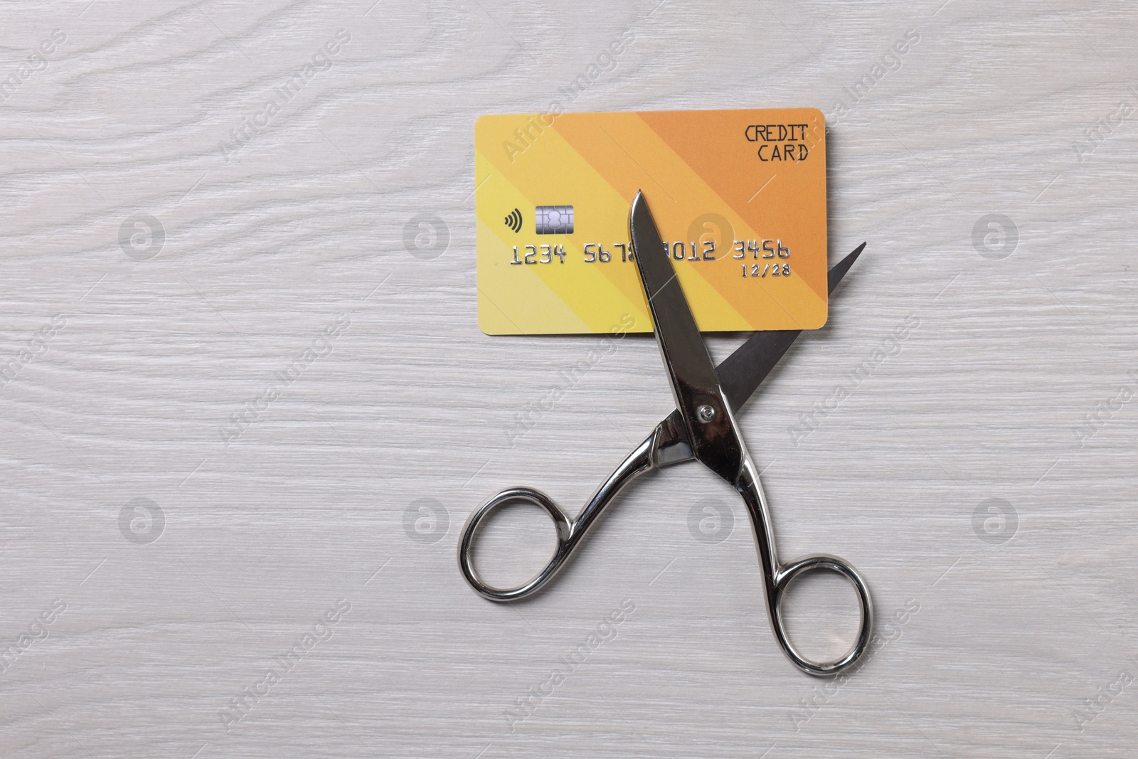 Photo of Credit card and scissors on white wooden table, top view. Space for text