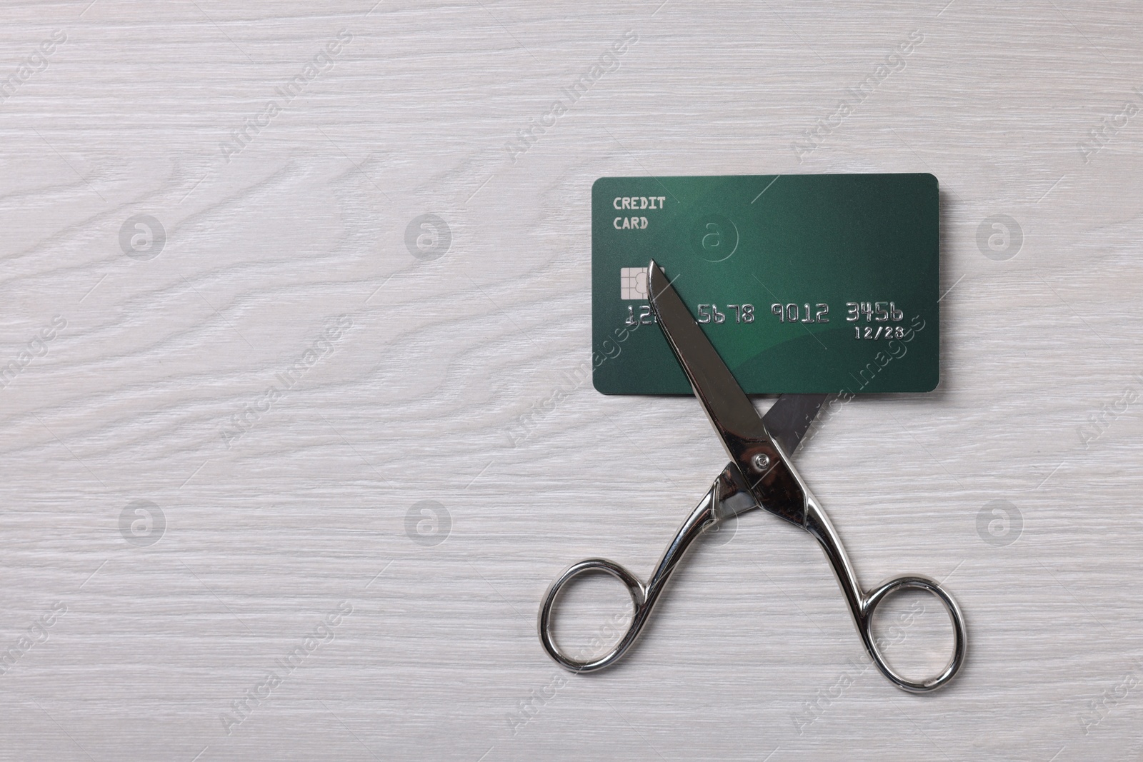 Photo of Credit card and scissors on white wooden table, top view. Space for text