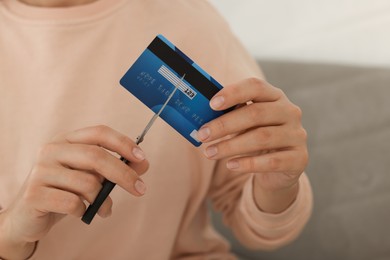 Photo of Woman cutting plastic credit card indoors, closeup