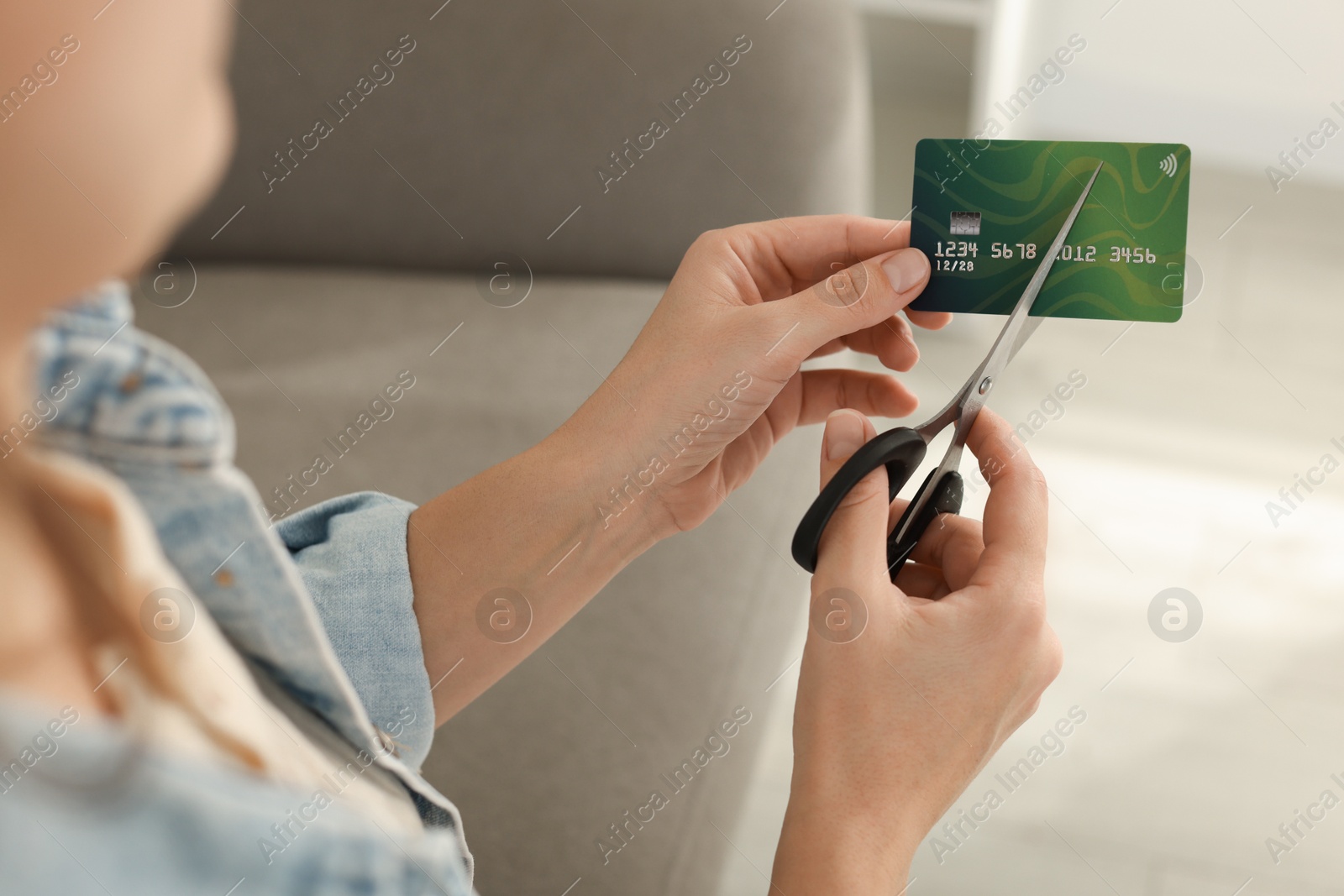 Photo of Woman cutting plastic credit card indoors, closeup