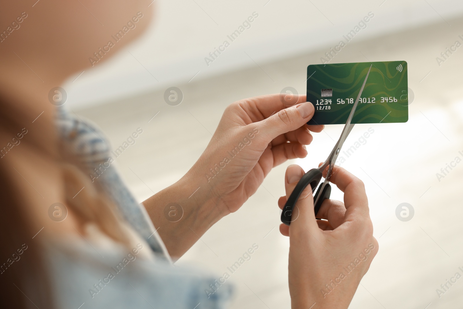 Photo of Woman cutting plastic credit card indoors, closeup