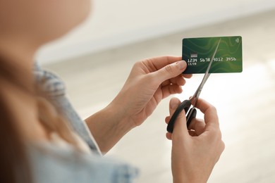 Photo of Woman cutting plastic credit card indoors, closeup