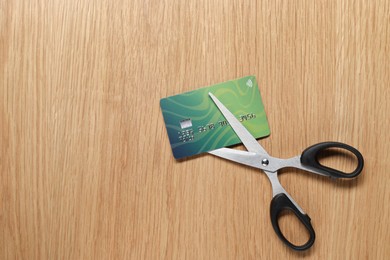 Photo of Credit card and scissors on wooden table, top view. Space for text