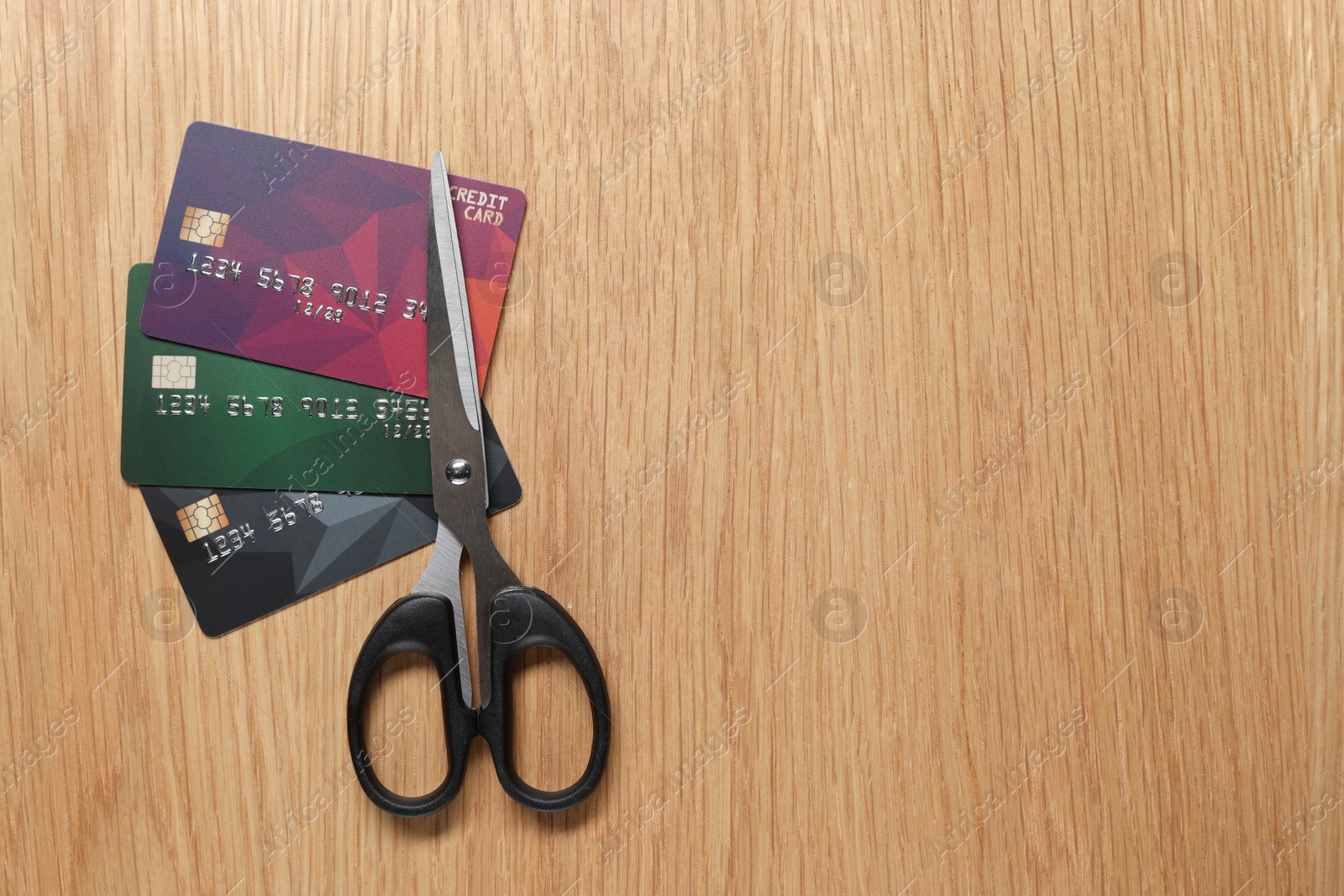 Photo of Credit cards and scissors on wooden table, top view. Space for text