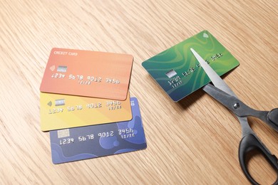 Photo of Credit cards and scissors on wooden table, closeup