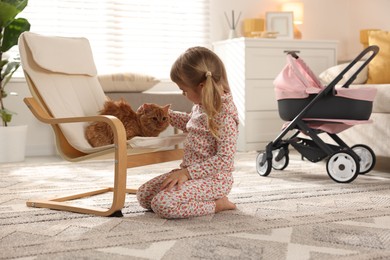 Photo of Cute little girl with her ginger cat at home