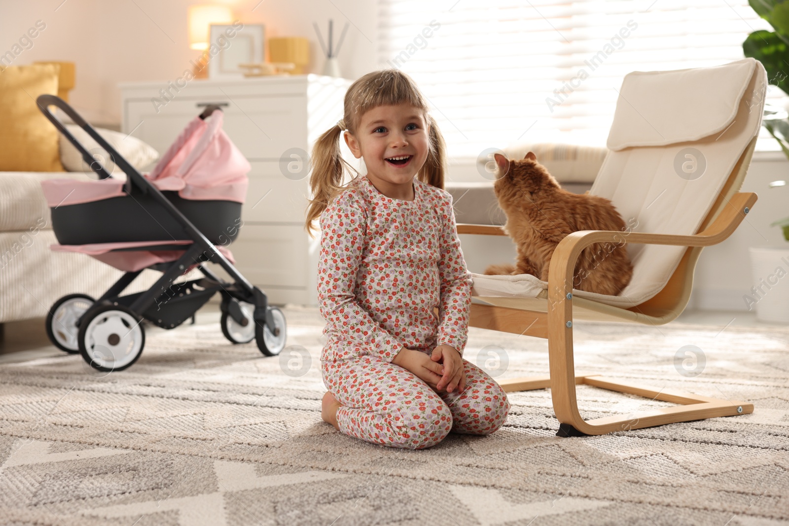 Photo of Cute little girl with her ginger cat at home