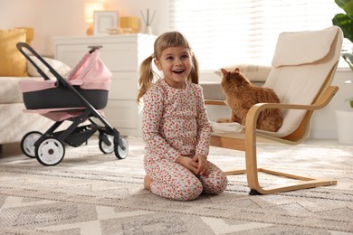 Photo of Cute little girl with her ginger cat at home