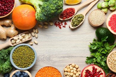 Photo of Frame of different superfood products on wooden table, flat lay. Space for text