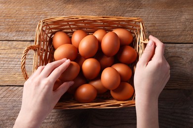 Photo of Woman with raw eggs at wooden table, top view