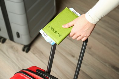 Photo of Woman with passport, tickets and suitcases indoors, closeup