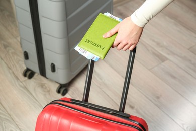 Photo of Woman with passport, tickets and suitcases indoors, closeup