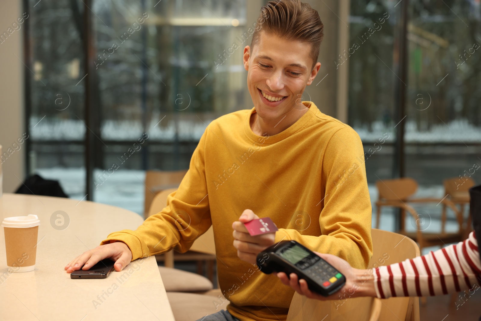 Photo of Man paying with credit card via terminal in cafe