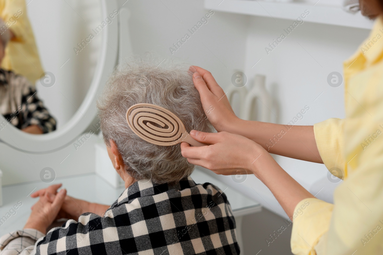 Photo of Woman brushing senior lady with brush indoors, closeup