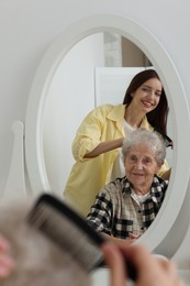 Photo of Woman brushing senior lady with comb indoors