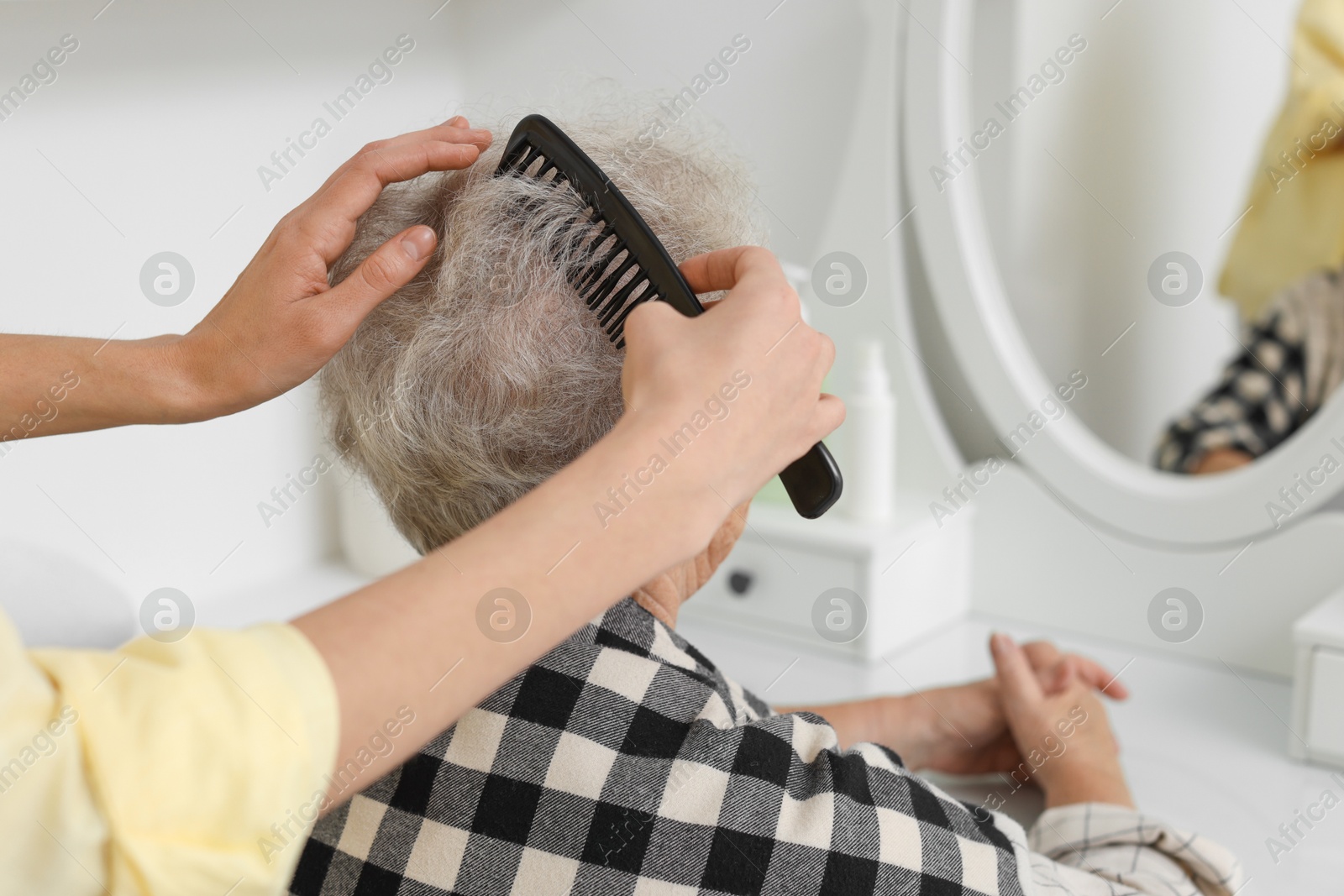 Photo of Woman brushing senior lady with comb indoors, closeup