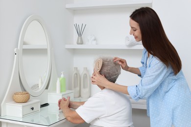 Photo of Woman brushing senior lady with brush indoors