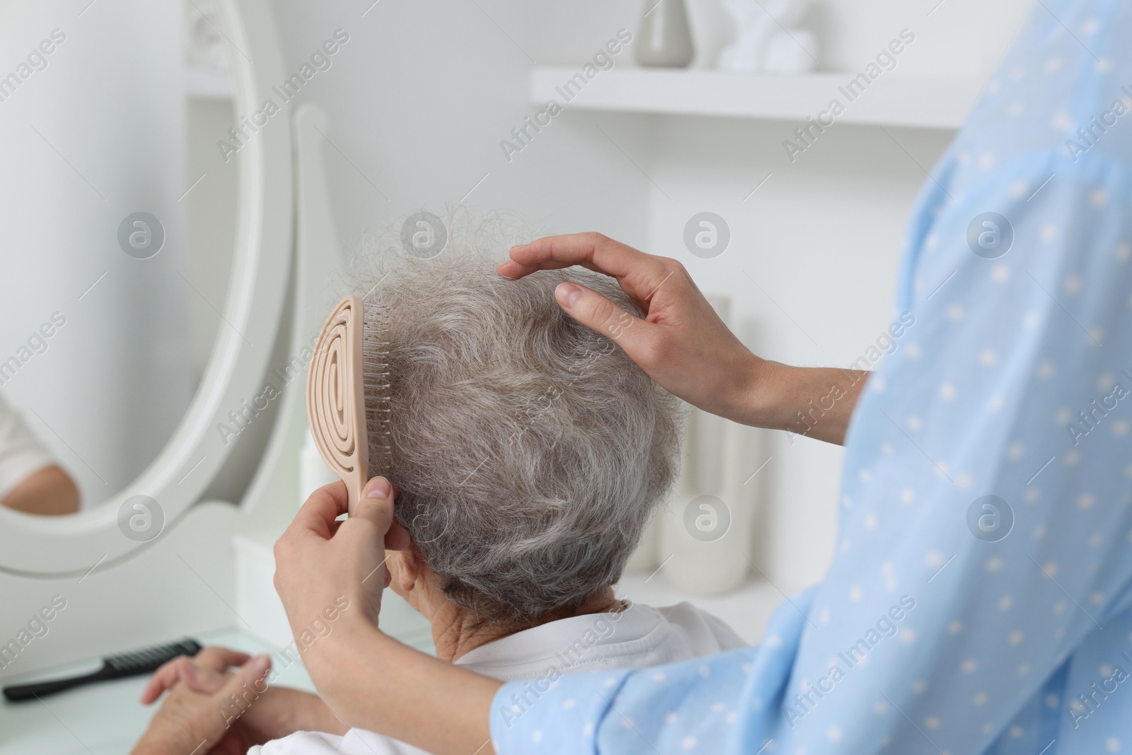 Photo of Woman brushing senior lady with brush indoors, closeup