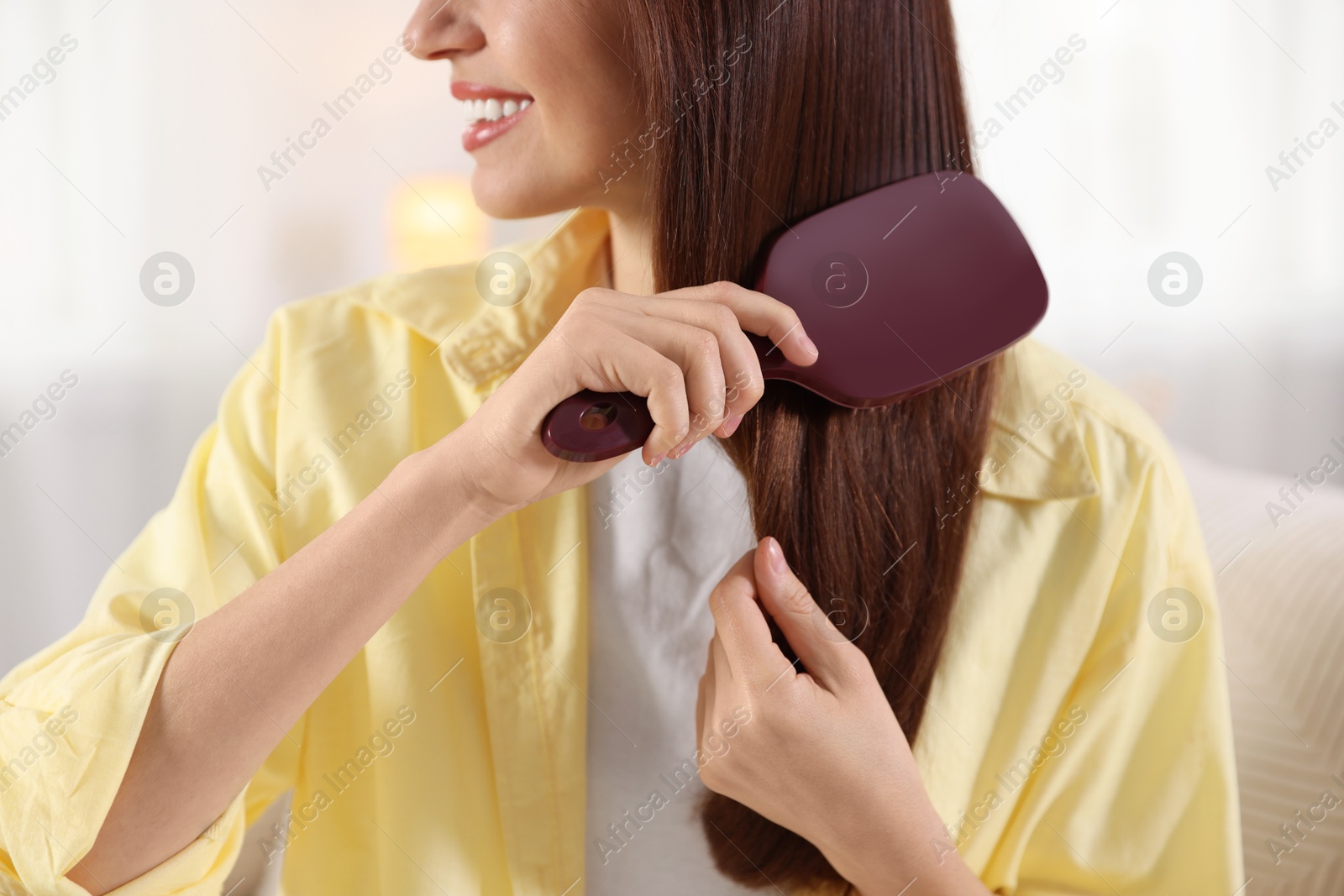 Photo of Woman brushing her hair at home, closeup