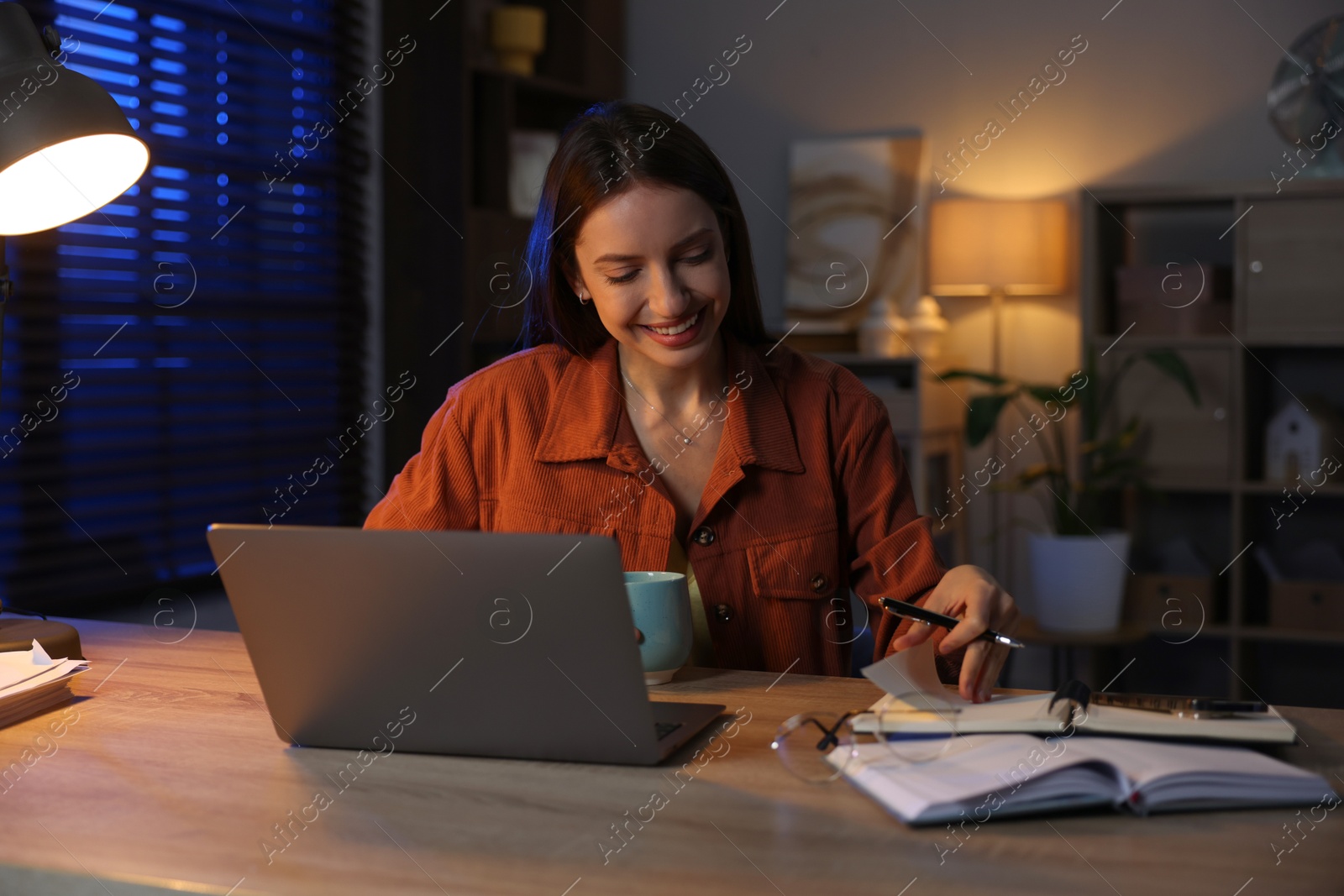 Photo of Woman taking notes while working at desk in home office