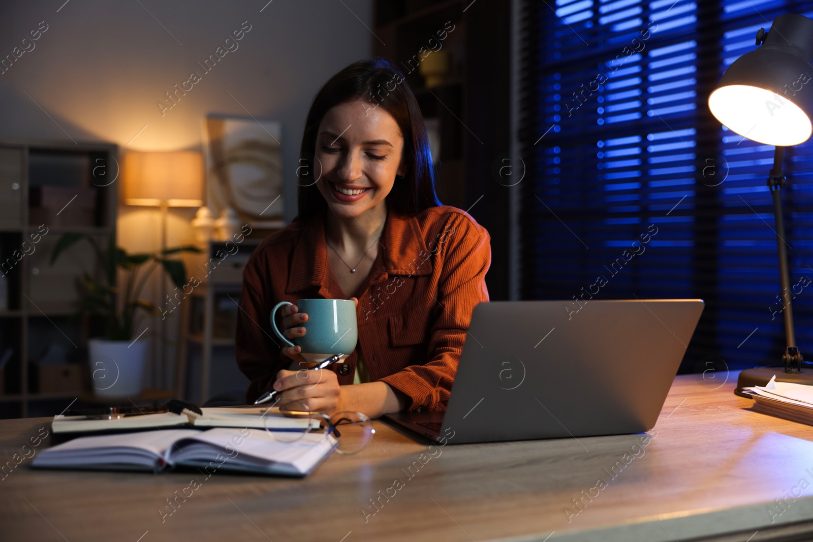 Photo of Woman taking notes while working at desk in home office