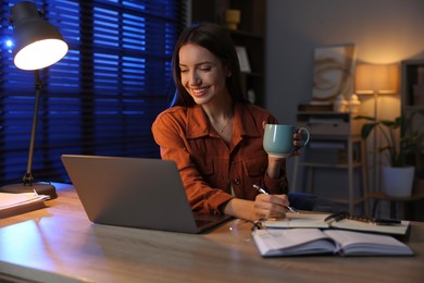 Photo of Woman taking notes while working at desk in home office